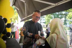 Pengasas Zoul’s Corner, Encik Azhar Mohd Salleh, mengagihkan bungkusan nasi ayam penyet percuma semasa acara pembukaan rasmi cawangannya yang keenam di Blk 204 Bedok North Street 1 pada 21 Oktober.