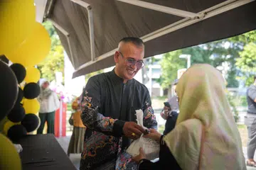 Pengasas Zoul’s Corner, Encik Azhar Mohd Salleh, mengagihkan bungkusan nasi ayam penyet percuma semasa acara pembukaan rasmi cawangannya yang keenam di Blk 204 Bedok North Street 1 pada 21 Oktober.