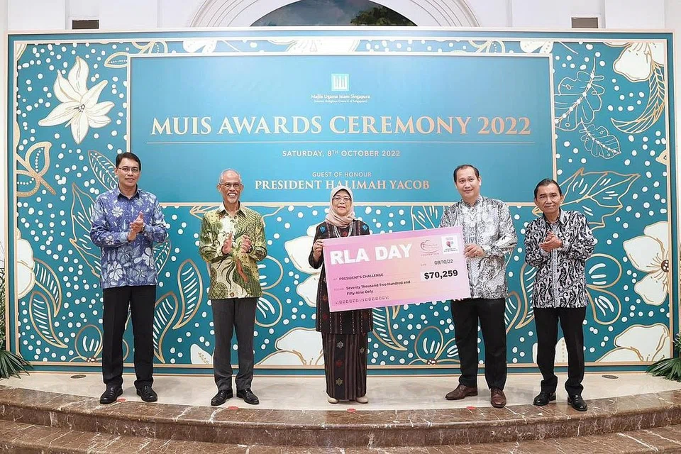 SEMANGAT RAHMAH: Encik Muhammad Faizal (dua dari kanan) menyampaikan cek bernilai $70,259 daripada RLAF kepada Puan Halimah bagi Cabaran Presiden semasa upacara Anugerah Muis 2022 di Istana, dengan disaksikan (dari kiri) Ketua Eksekutif Muis, Encik Kadir Maideen; Menteri Bertanggungjawab bagi Ehwal Masyarakat Islam, Encik Masagos Zulkifli Masagos Mohamad; serta Presiden Muis, Encik Saat A. Rahman. - Foto MCI