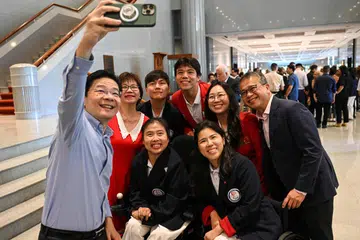 Perdana Menteri, Encik Lawrence Wong (paling kiri), berswafoto dengan atlet yang mewakili Singapura di Sukan Paralimpik dan Olimpik Paris di Parlimen pada 16 Oktober. Bersama mereka adalah Menteri Kebudayaan, Masyarakat dan Belia, Encik Edwin Tong (paling kanan).