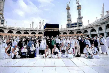 KENANGAN DI DEPAN KAABAH: Para jemaah yang mengikuti rombongan dari TravelConnect.sg bergambar di depan Kaabah. Ramai masyarakat Islam Singapura memilih untuk ke Tanah Suci pada musim percutian ini. - Foto TRAVELCONNECT.SG