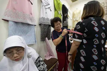 TETAP TEGUH DAN YAKIN DENGAN REKAAN: Cik Lie Hong Haw pemilik Butik Bewa Fashion tekun melayan pelanggan. Butik ini ditutup dalam tempoh pemutus litar, namun masih menjual di platform dalam talian. - Foto fail 2019