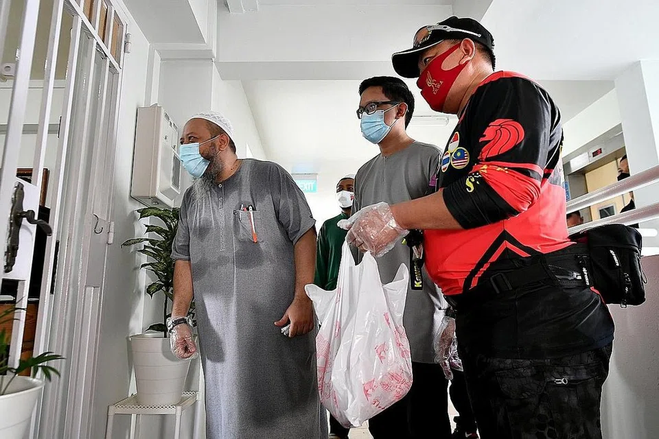 BANTU AGIH DAGING KORBAN: (Dari kiri) Encik Adlee Nazree Suparman, pengarah A2A Trading, yang membawa masuk daging korban dari Australia ke Singapura; Ustaz Abdullah Al-Muaz; dan relawan penyelaras kumpulan Friends Bikers & Twenty20 Bikers, Encik Mohammed Nizam Elmi, mengagihkan daging korban kepada salah sebuah keluarga penerima zakat yang menetap di flat sewa di Blok 182 Rivervale Cresent, semalam. - Foto BH oleh LIM YAOHUI