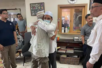 PEMERGIAN MENINGGALKAN KESAN: Mufti Dr Nazirudin dilihat berdakapan dengan bapa Allahyarham, Encik Sunawan, ketika melawat jenazah Allahyarham Riz Sunawan semalam. Turut hadir ialah Timbalan Ketua Eksekutif Muis, Dr Albakri Ahmad (paling kanan). - Foto BH oleh SITI AISYAH NORDIN