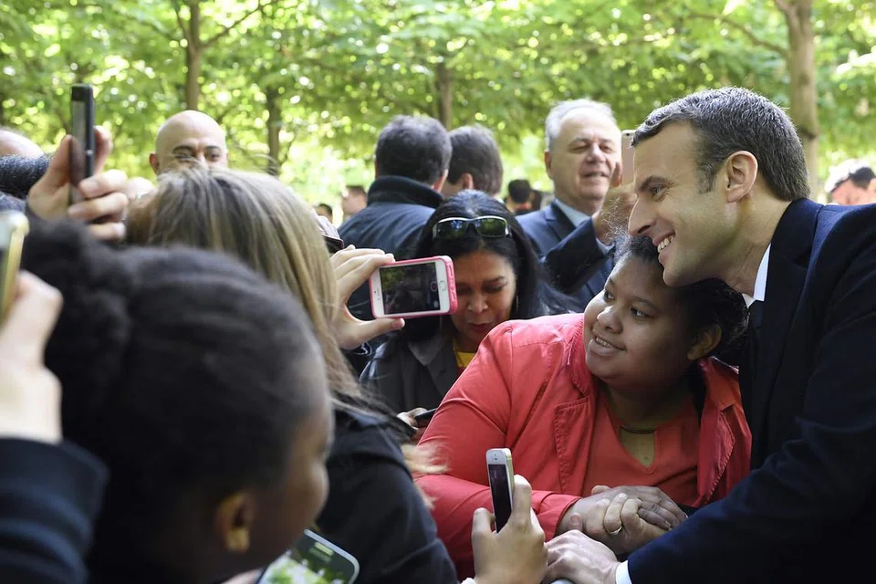 'DIBURU' PEMINAT: Presiden baru Perancis, Encik Emmanuel Macron (kanan), bergambar dengan penyokongnya semasa menghadiri satu acara bagi meraikan ulang tahun tamatnya amalan penghambaan di Jardins du Luxembourg di Paris minggu lalu. - Foto AFP 