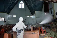 BASMI KUMAN: Seorang pekerja kesihatan melakukan pembasmian kuman di Gereja Santa Maria di Palu, Jawa Tengah, semalam, sedang masyarakat Kristian meraikan perayaan Hari Natal esok. - Foto AFP