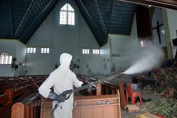 BASMI KUMAN: Seorang pekerja kesihatan melakukan pembasmian kuman di Gereja Santa Maria di Palu, Jawa Tengah, semalam, sedang masyarakat Kristian meraikan perayaan Hari Natal esok. - Foto AFP