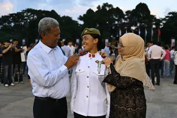 Leftenan Muda Zakiah Huda Sapari (tengah), 25 tahun, bersama ayahnya, Encik Sapari Mingan,  dan ibu, Cik Sapiah Abdul Aziz. Ayahnya dilihat menampalkan tanda pangkat pegawai di bahunya semasa di Perbarisan Pentauliahan Pegawai Kadet. 
