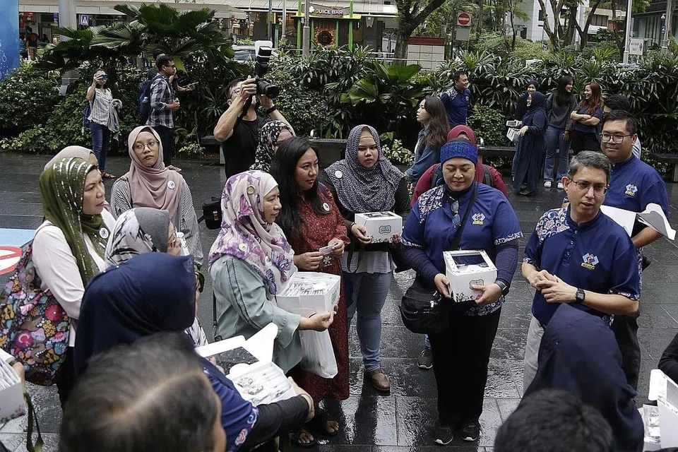 MENGERATKAN SILATURAHIM : Dr Faishal (kanan) bersama relawan Mesra, MAEC dan daripada beberapa masjid hadir di Orchard Road Sabtu lalu untuk memberi biskut buatan sendiri kepada masyarakat bangsa lain sempena perayaan Krismas. - Foto BH oleh AZMI ATHNI