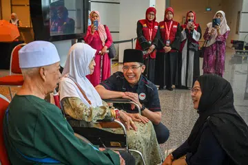 Menteri di Pejabat Perdana Menteri, Dr Mohamad Maliki Osman (dua dari kanan), berbual dengan Cik Sapiah Mamat (dua dari kiri), 88 tahun, jemaah haji paling tua dalam rombongan pada 2024. Cik Sapiah, yang bersemangat walaupun menghadapi masalah mobiliti, penyakit darah tinggi dan jantung, ghairah untuk menunaikan ibadah haji.