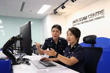 PANTAU KES PENIPUAN: Penolong Superintenden Polis (ASP) Claire Chiang (kiri) dan ASP Joan Liu (kanan) memantau laporan polis tentang kes penipuan yang difailkan mangsa di Pusat Anti-Penipuan (ASC) di Police Cantonment Complex.