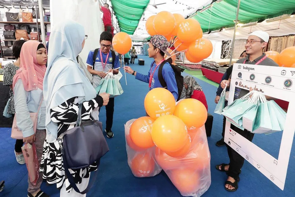 SEBARKAN RAHMAH: Sukarelawan memberi belon dan bag hadiah kepada orang ramai di sekitar bazar Geylang Serai sebagai sebahagian kempen Sentuhan Ramadan tahun ini. - Foto BH oleh KELVIN CHNG 