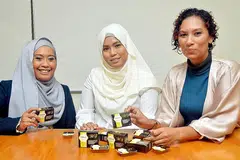 TEMBUSI PASARAN EKSPORT: (Dari kiri) Cik Masturah dengan rakan niaganya, Cik Nurlela, menunjukkan produk sabun yang dihasilkan mereka, sambil diperhatikan Cik Aida. - Foto KHALID BABA
