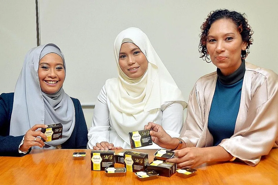 TEMBUSI PASARAN EKSPORT: (Dari kiri) Cik Masturah dengan rakan niaganya, Cik Nurlela, menunjukkan produk sabun yang dihasilkan mereka, sambil diperhatikan Cik Aida. - Foto KHALID BABA