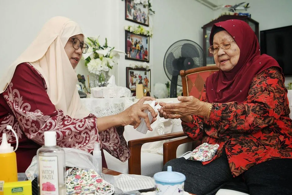 HASILKAN SENDIRI: Cik Juriah Yatim (kiri) telah belajar menghasilkan bahan pembersih tangan dan pelitup sendiri di rumah. Dengan orang di rumah dianggap golongan lebih berisiko, Cik Juriah masih mematuhi peraturan dengan rapi. Bersama beliau ialah ibunya, Cik Ramlah Raes. - Foto BH oleh KHALID BABA