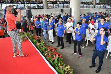 SENAM BERSAMA: Encik Masagos Zulkifli Masagos Mohamad (barisan depan, tiga dari kanan), Cik Indranee Rajah (barisan depan, dua dari kanan) dan tetamu lain seperti Presiden Muis Haji Mohammad Alami Musa (barisan depan, kanan) senam bersama lebih 800 pekerja asing dan 600 pegawai serta relawan masjid Singapura dalam Hari RLA di Bendungan Marina semalam. - Foto MUIS