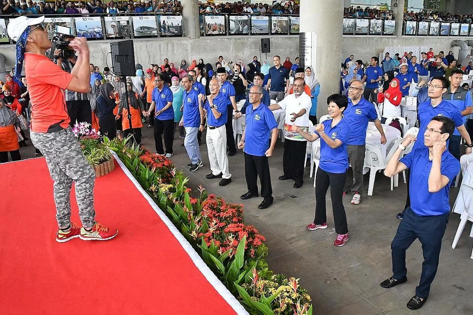 SENAM BERSAMA: Encik Masagos Zulkifli Masagos Mohamad (barisan depan, tiga dari kanan), Cik Indranee Rajah (barisan depan, dua dari kanan) dan tetamu lain seperti Presiden Muis Haji Mohammad Alami Musa (barisan depan, kanan) senam bersama lebih 800 pekerja asing dan 600 pegawai serta relawan masjid Singapura dalam Hari RLA di Bendungan Marina semalam. - Foto MUIS