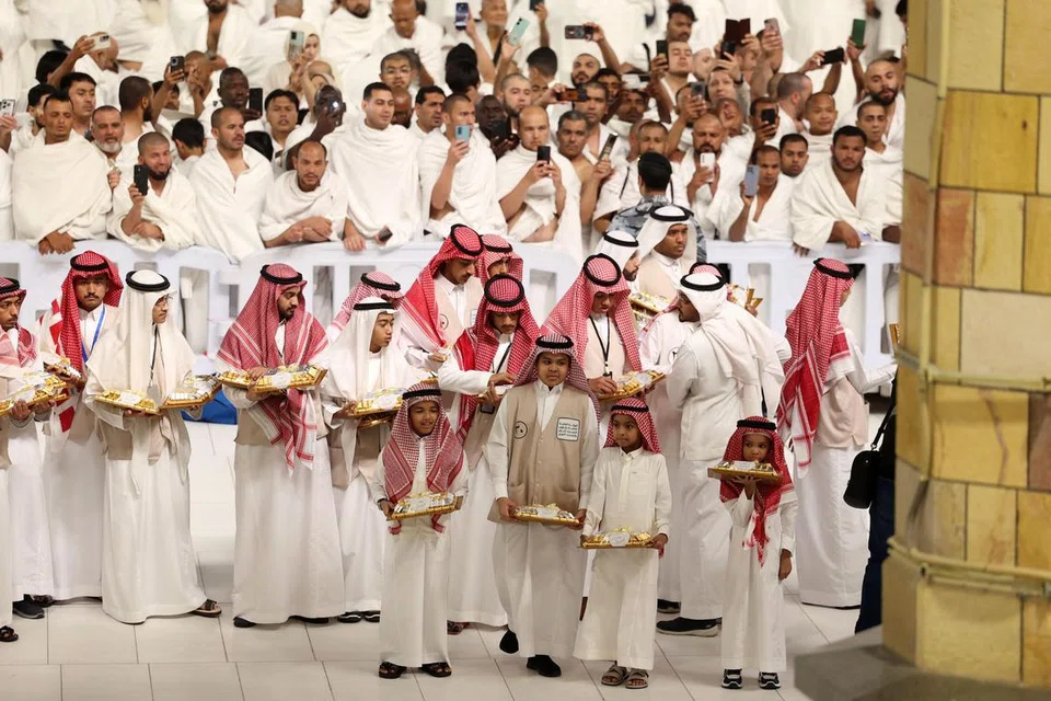 Para sukarelawan bersiap sedia mengagihkan manisan ketika umat Islam berhimpun menunaikan solat sunat Aidilfitri di Masjidil Haram pada awal pagi 30 Mac.