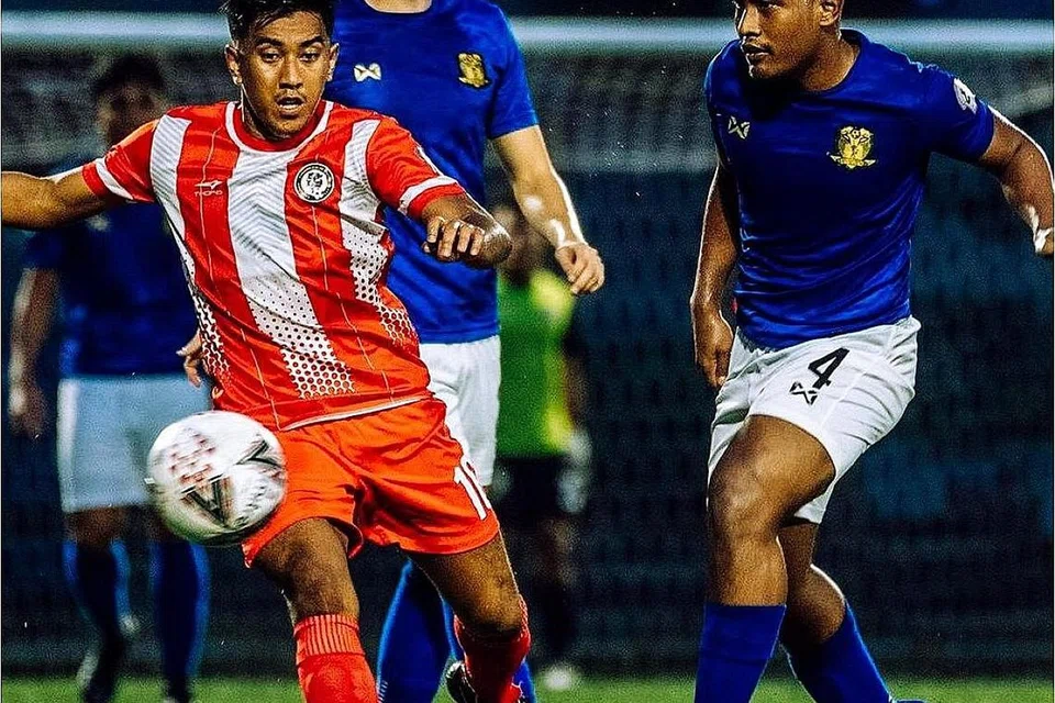 SERI: Pemain Tanjong Pagar Raihan Rahman (baju merah putih) cuba mengawal bola dan melepaskan diri dari pemain Hougang United dalam perlawanan yang berakhir seri 0-0. - Foto SPL 