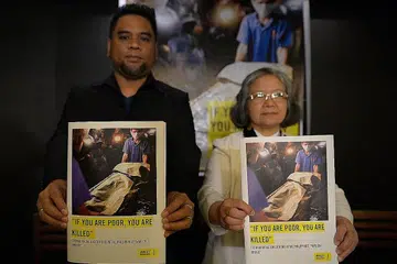 BENTANGKAN LAPORAN: Encik Wilnor Papa dan Sister Maria Cordero, daripada Amnesty International bersama salinan laporan mereka yang menunjukkan gambar mayat pesalah dadah yang ditembak mati pihak polis. - Foto AFP