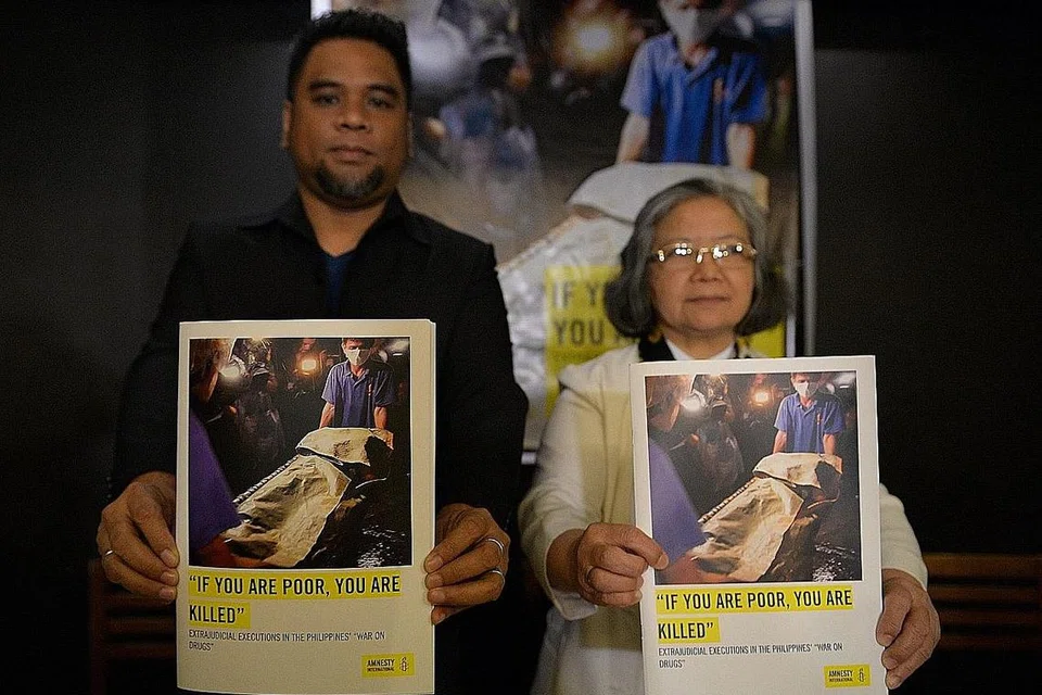 BENTANGKAN LAPORAN: Encik Wilnor Papa dan Sister Maria Cordero, daripada Amnesty International bersama salinan laporan mereka yang menunjukkan gambar mayat pesalah dadah yang ditembak mati pihak polis. - Foto AFP