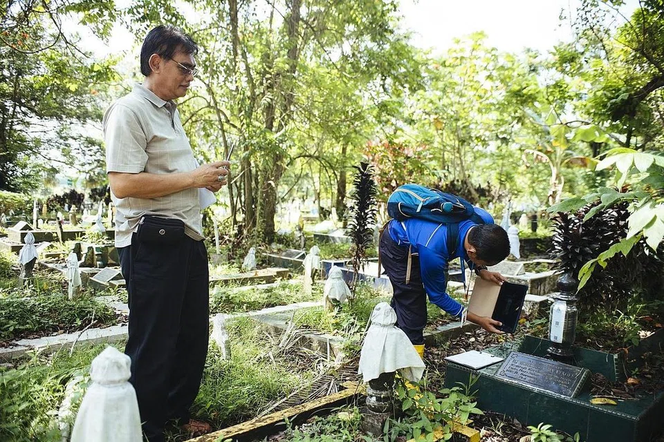 DITANDA SECARA ELEKTRONIK: Encik Rahim mengambil gambar kubur arwah ayahnya selepas mengenal pasti kubur itu dengan disaksikan seorang pegawai dari Pejabat Penggalian dan Pengebumian Semula. Kubur yang dikenal pasti itu akan ditandakan dengan kod QR unik yang kalis air, sementara menanti tarikh ia digali semula. - Foto BH oleh ALVIN HO