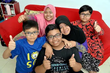 KECAPI JAYA WALAU AYAH TIADA: Muhammad Nur Fadhli Zulkefli (berbaju biru gelap) menerima keputusan yang menggembirakan hati ibunya, Cik Rohaya Zainal Abidin (bertudung hitam) dalam peperiksaan GCE 'O' tahun lalu dan kini menjadi contoh baik bagi tiga adiknya iaitu Siti Nur Aisyah (bertudung merah jambu), Siti Nur Raudhah dan Muhammad Nur Firdaus. - Foto M.O. SALLEH