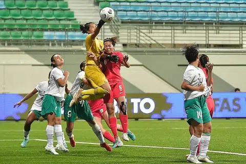 CUBA REBUT BOLA: Pemain Singapura, Nur Farhanah (jersi merah), melompat tinggi untuk cuba menanduk bola semasa menentang Indonesia kelmarin. - Foto BH oleh DESMOND WEE