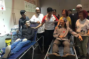 GEMENTAR TUNGGU GILIRAN: Dr Fatimah (tengah) bersembang bersama dua penderma darah (duduk dari kiri) Encik Charleston Lim dan Encik Nadhar Ramli sambil diiringi pemimpin badan agama dari gereja Heart of God Church (HOGC), Masjid Khalid dan Kuil Geylang United. - Foto FAKHRURADZI ISMAIL