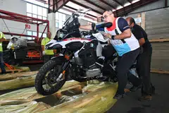 (dari kanan) Encik Mohamed Yusof Mohamed dan Encik Mohd Anis Mohd Kassim memuatkan motosikal ke atas kayu palet supaya dapat dimuatkan ke dalam kontena pada 6 Disember 2024 untuk dihantar ke Karachi, Pakistan.
