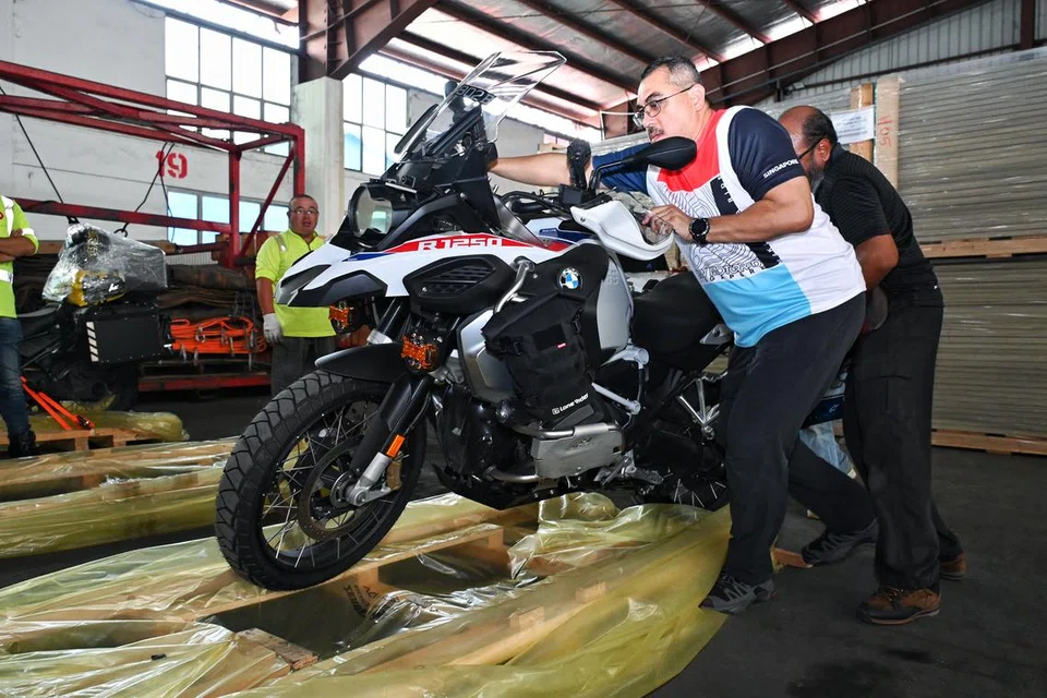 (dari kanan) Encik Mohamed Yusof Mohamed dan Encik Mohd Anis Mohd Kassim memuatkan motosikal ke atas kayu palet supaya dapat dimuatkan ke dalam kontena pada 6 Disember 2024 untuk dihantar ke Karachi, Pakistan.