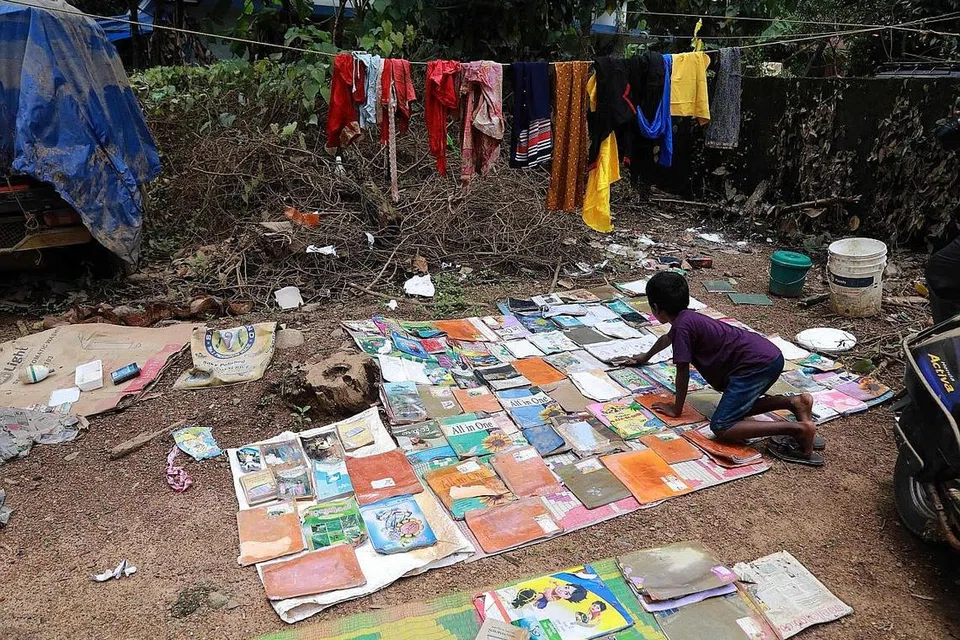 PELAJARAN TETAP PENTING: Seorang pelajar mengeringkan buku sekolahnya yang basah ekoran banjir yang melanda kediamannya di Kochi, Kerala. - Foto AFP
