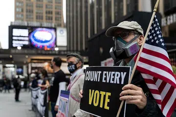 JUMLAH REKOD PENGUNDI: Seorang lelaki memakai topeng pelindung disebabkan pandemik Covid-19, memegang papan tanda di luar Madison Square Garden, yang digunakan sebagai tempat mengundi, pada hari pertama pengundian awal di Manhattan, New York, pada 24 Oktober. Terdapat jumlah rekod pengundi semasa pengundian awal di seluruh Amerika Syarikat dalam pilihan raya presiden antara calon Republik Presiden Donald J. Trump dan calon Demokrat mantan naib presiden Joe Biden. - Foto REUTERS 