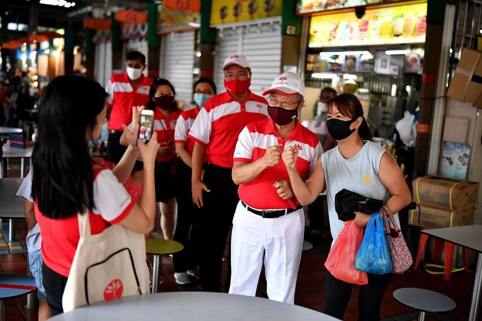 TETAP BERSEMANGAT: Walau tumpas, Dr Tan Cheng Bock (dua dari kanan) yang menerajui Parti Kemajuan Singapura (PSP) di GRC West Coast mengucapkan terima kasih dan bergambar dengan penduduk di Pusat Makan Ayer Rajah semalam. - Foto BH oleh LIM YAOHUI