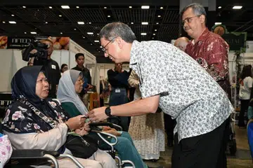 Cik Suriani Sabudin (kiri) menerima Paket Dana TAA daripada Menteri Negara (Ehwal Dalam Negeri merangkap Pembangunan Negara), Profesor Madya Dr Muhammad Faishal Ibrahim,  semasa majlis pengagihan TAA Ramadan 2024 di Celebfest, Suntec City, pada 31 Mac. 