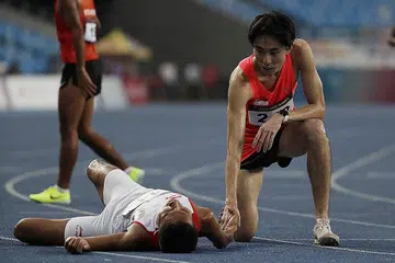 JADI INSPIRASI: Pelari Singapura Soh Rui Yong (kanan) mendapat pujian ramai kerana memberi secawan air kepada pesaingnya, Rikki Marthin Luther Simbolon, dalam acara final 10,000 meter lelaki. - Foto-foto REUTERS