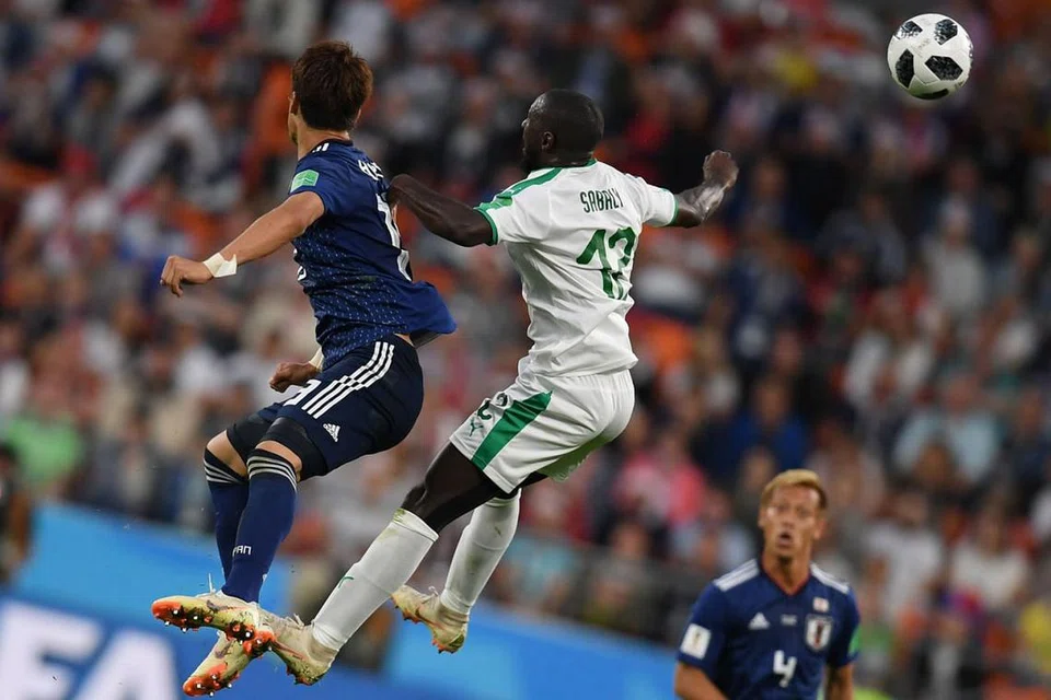 BERSAING SENGIT: Pemain Jepun Hiroki Sakai (jersi biru) bersaing menanduk bola dengan pemain Senegal Youssouf Sabaly dalam pertandingan yang berakhir dengan seri 2-2 kelmarin. - Foto AFP 