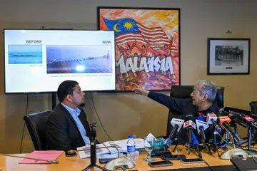 Mantan Perdana Menteri Malaysia, Tun Dr Mahathir Mohamad (kanan), menunjuk ke arah skrin tentang Pedra Branca semasa sidang media di Yayasan Kepimpinan Perdana, Putrajaya pada 10 Disember.