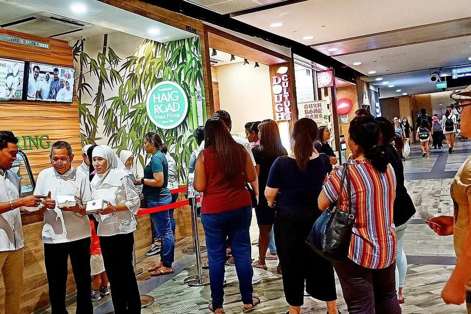 SEMAKIN BERKEMBANG: Encik Hashim (dua dari kiri), Cik Noorzela (tiga dari kiri) dan Encik Razali (kiri) turun padang memantau perniagaan di cawangan terbaru Traditional Haig Road Putu Piring, iaitu yang keenam, di Northpoint City, Yishun.