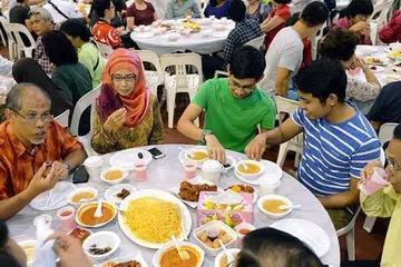 BERBUKA BERSAMA MASYARAKAT: Encik Masagos dan isteri, Cik Jumelah Ja'afar, bersama anak mereka Masagos Khalid (berbaju hijau) dan Masagos Umar menghadiri majlis iftar yang diadakan di Tampines West CC. - Foto KHALID BABA