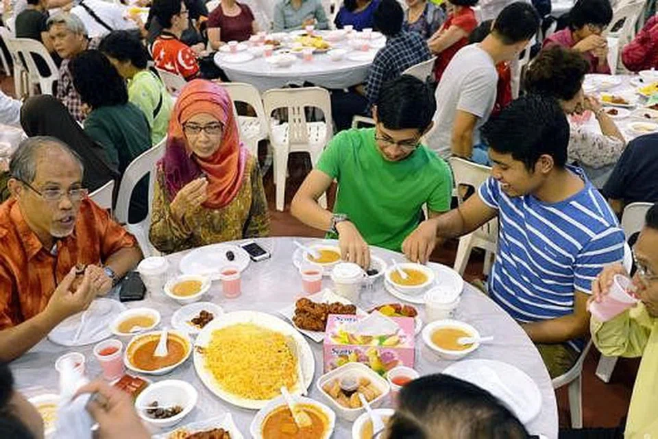 BERBUKA BERSAMA MASYARAKAT: Encik Masagos dan isteri, Cik Jumelah Ja'afar, bersama anak mereka Masagos Khalid (berbaju hijau) dan Masagos Umar menghadiri majlis iftar yang diadakan di Tampines West CC. - Foto KHALID BABA
