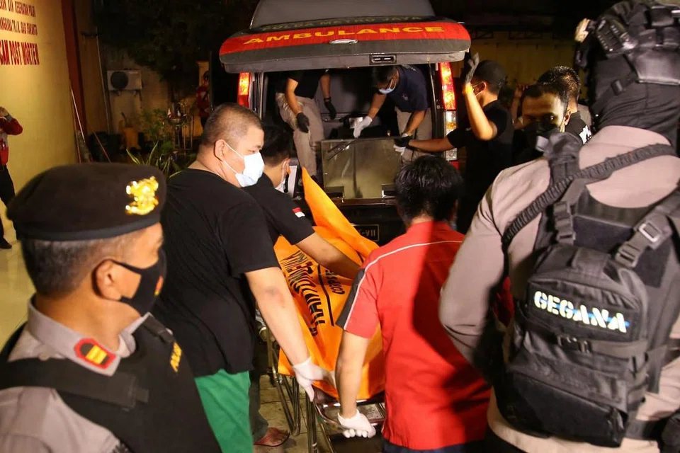 BERJAYA DITEMBAK MATI: Pegawai polis mengangkat mayat wanita yang cuba menyerang anggota polis di ibu pejabat polis Indonesia di Jakarta pada 31 Mac lalu. - Foto AFP