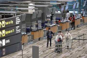 PAKAI PPE SEBELUM BERANGKAT: Beberapa individu dilihat memakai peralatan perlindungan peribadi (PPE) penuh sambil mendaftar masuk di kaunter Singapore Airlines di Terminal 3 Lapangan Terbang Changi semalam. - Foto BH oleh KEVIN LIM