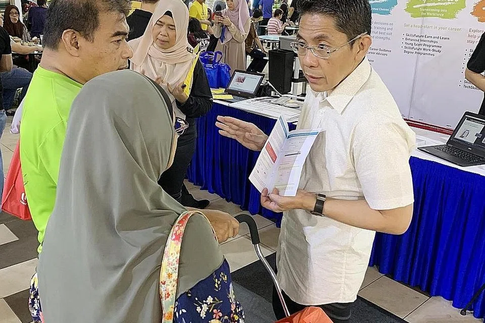 MENERANGKAN MANFAAT SKILLSFUTURE: Menteri Negara Kanan (Pertahanan merangkap Ehwal Luar), Dr Mohamad Maliki Osman, (berbaju putih) menerangkan tentang SkillsFuture kepada pengunjung ke pasar Geylang Serai semasa 'roadshow' yang diadakan di sana pada 24 November 2018. - Foto fail