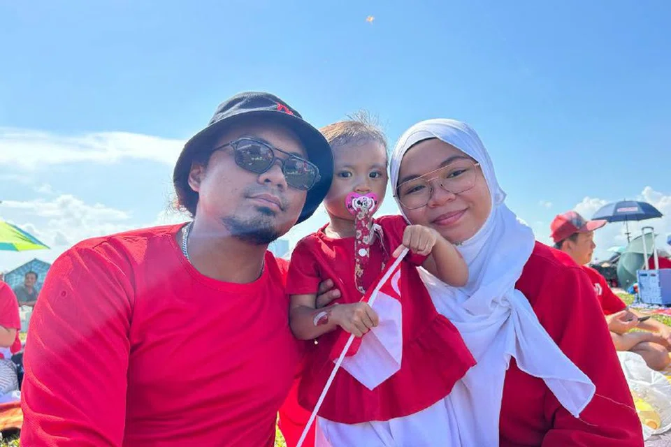 NIKMATI SUASANA SEKELUARGA: Encik Muhammad Haris Roslan dan isterinya Cik Nur Zuhairah Murad bersama puteri mereka berusia dua tahun, Nafiatul Hazimah, berada di Bendungan Marina bagi menikmati suasana NDP sejak 2 petang pada Rabu.