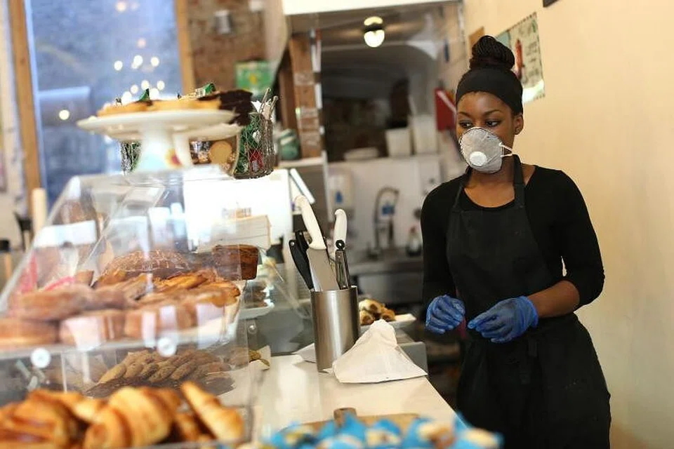 MASIH BERJAGA-JAGA: Seorang pembantu kedai roti dan kek dilihat memakai alat pelindung diri, termasuk pelitup sebagai melindungi keselamatan diri terhadap jangkitan Covid-19 di England's Lane di utara London pada 19 Mei lalu. 