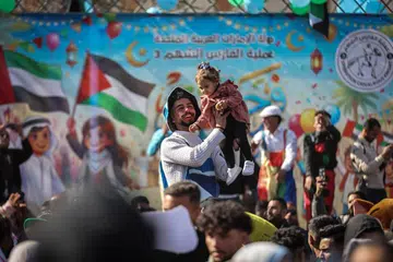 Seorang lelaki mendukung seorang kanak-kanak perempuan semasa acara hiburan buat si cilik pada hari ketiga sambutan Aidilfitri, yang menandakan berakhirnya Ramadan, di Bandar Gaza, pada 22 Mac 2026.