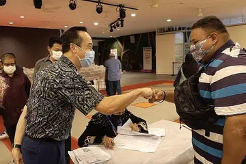 BERTEMU MESRA: Tamu terhormat acara pengagihan daging korban terakhir Jamiyah tahun ini, Dr Koh Poh Koon (kiri), melakukan 'fist bump' dengan penerima daging korban di Tampines semalam. - Foto JAMIYAH SINGAPURA