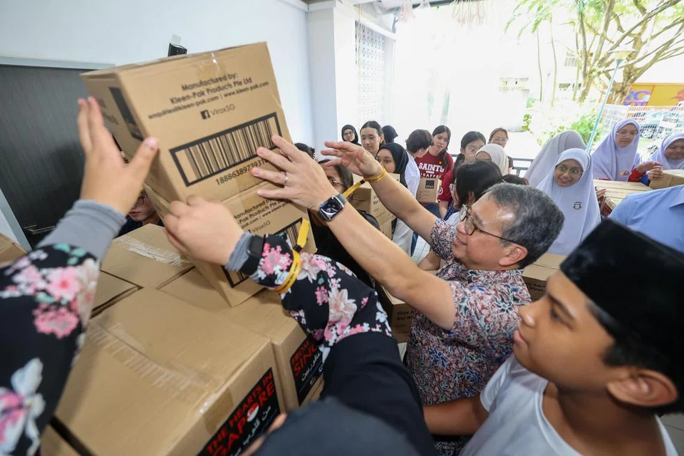 Menteri Kebudayaan, Masyarakat dan Belia merangkap Menteri Kedua Undang-Undang, Encik Edwin Tong (dua dari kanan), membantu sukarelawan di Madrasah Aljunied mengangkat bungkusan bantuan bagi mereka yang terjejas di Gaza.