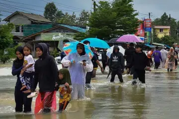 DITENGGELAMI AIR: Para penduduk di Narathiwat, wilayah selatan Thailand, mengharungi paras air tinggi untuk menuju ke tempat yang lebih selamat ekoran banjir melanda wilayah itu pada 25 Disember.